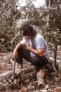 Full length of young man sitting in forest