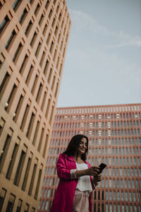 Portrait of smiling woman standing against building