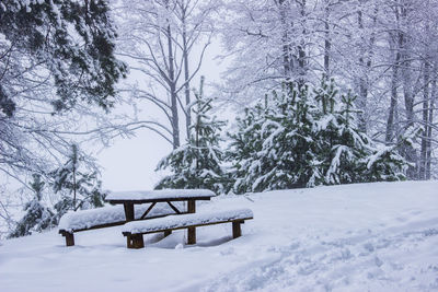 Empty bench on snow covered field during winter