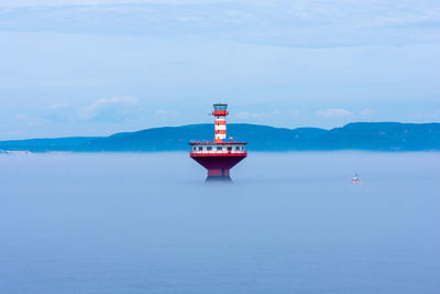 Lighthouse in sea against blue sky