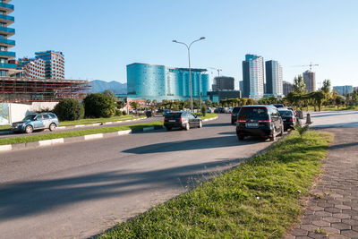 Cars on road by buildings against clear sky