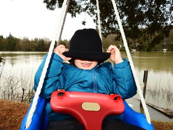 Happy girl enjoying swing at lakeshore