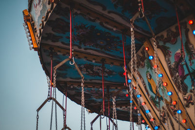 Low angle view of chain swing ride against clear sky