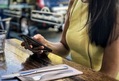 Midsection of woman using mobile phone on table