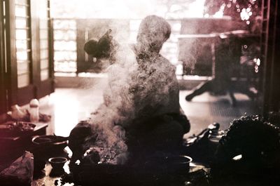 Silhouette man sitting in front of smoke at home