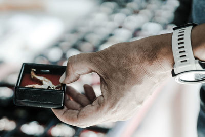 Midsection of man holding jewelry