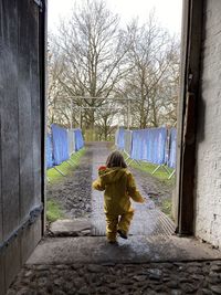 Young girl running from building into muddy winter scene