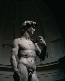 Low angle view of shirtless man standing against wall