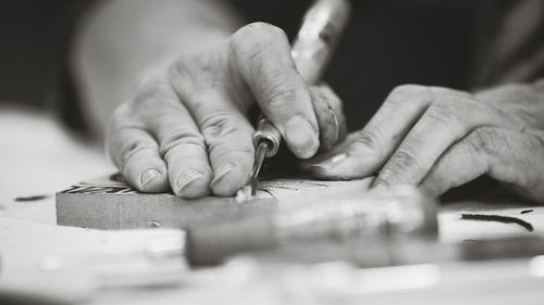 Cropped hands of carpenter carving wood in workshop