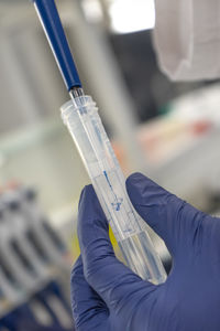 The lab technician performs the experiment by injecting the blue liquid into a test tube
