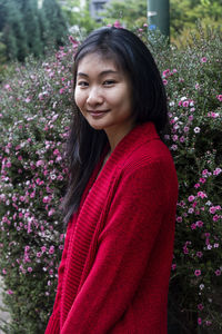 Portrait of smiling woman standing by flowering plants