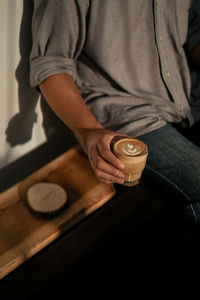 Midsection of man holding drink on table