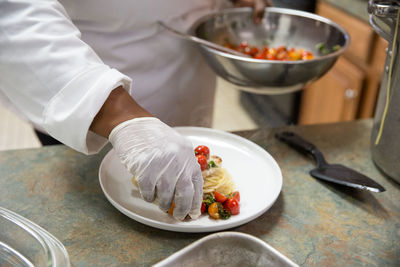 Midsection of chef preparing food in kitchen at restaurant