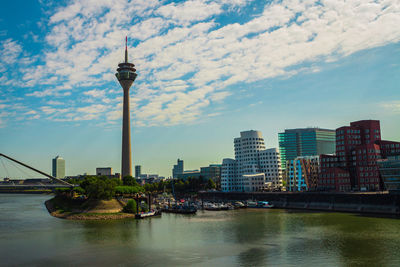 View of buildings at waterfront against cloudy sky over dusseldorf 