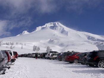 Cars parked by snowcapped mountain against sky