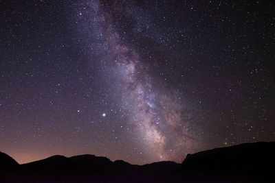 Low angle view of silhouette mountain against sky at night