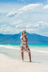 Woman standing on beach by sea against sky