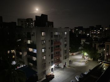 High angle view of illuminated street amidst buildings in city at night