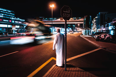 Rear view of mature man standing on road at night