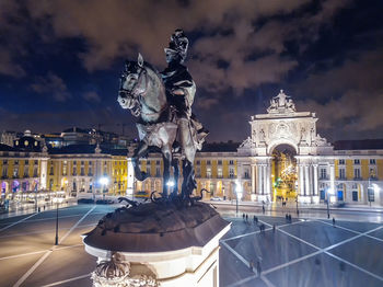 Statue in city against cloudy sky