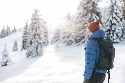 Man on a hike in the snow during winter, at sunset time.