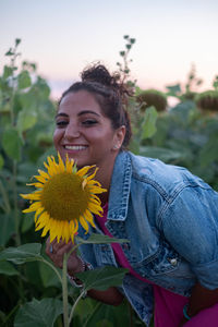 Smiling young woman with sunflower plants