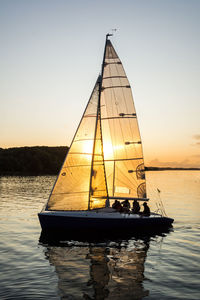 Sailboat sailing on sea against clear sky during sunset