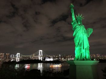 Statue of illuminated city against cloudy sky