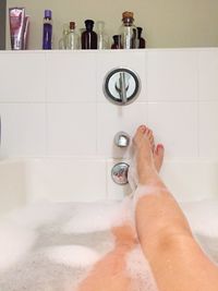 Low section of woman relaxing in bathtub