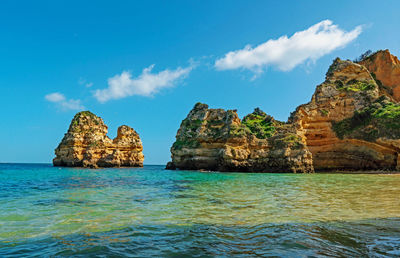 Rock formations in sea against blue sky