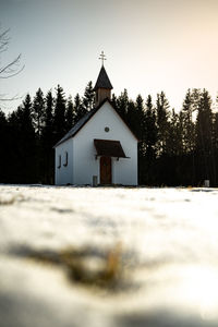 Snowy land and church against clear sky