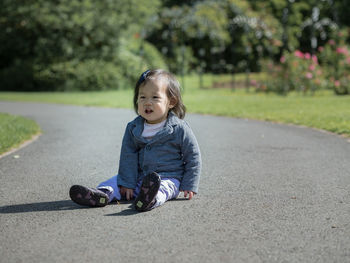 Portrait of young girl sitting on footpath