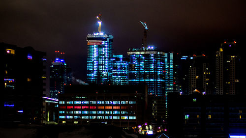 Illuminated cityscape against sky at night