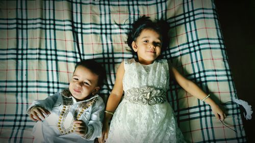 Portrait of cute siblings lying on bed at home