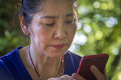 Close-up portrait of woman using smart phone outdoors