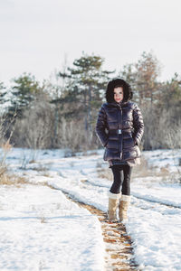 Full length of teenage girl standing on snow covered land