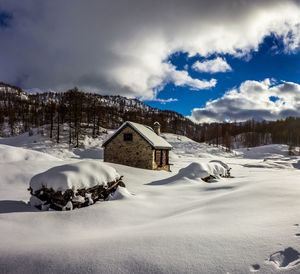 Snow covered landscape and buildings against sky