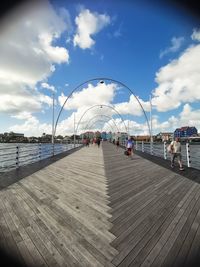 People on pier by sea against sky