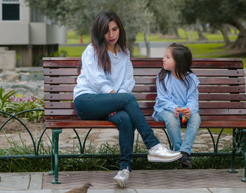 Full length of woman sitting on bench in park