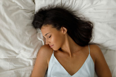 Close-up of young woman lying on bed at home