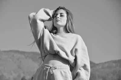 Young woman standing against sky