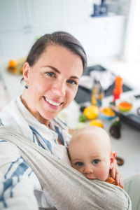 High angle portrait of smiling mother and daughter in kitchen at home