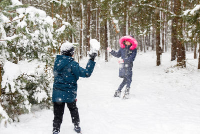 Funny children in winter park playing snowballs, actively spending time outdoors. winter snowy 