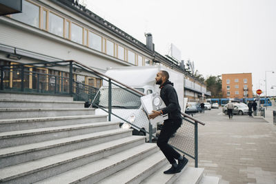 Side view of man walking on staircase in city