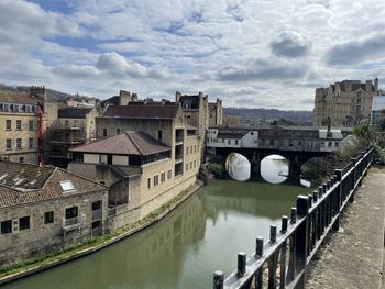 Bridge over river amidst buildings in city against sky