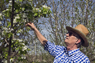 Close-up of senior man standing by plant outdoors