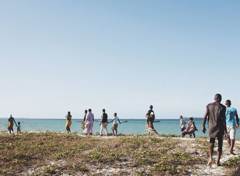 People on beach against clear sky