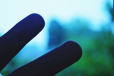 Close-up of human hand against blue sky