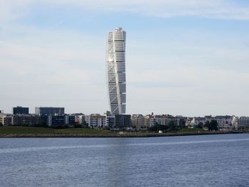 Sea by buildings against sky in city