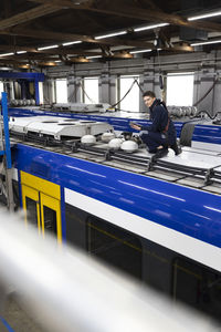 Engineer holding tablet pc sitting on monorail rooftop in industry